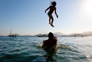 Father in ocean, playfully tossing child.