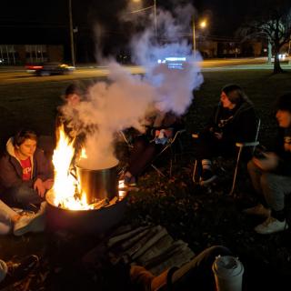 Youth sitting around firepit during Homeless on Hillard event