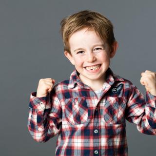 White boy about eight years old showing confident excitement and wearing a plaid shirt