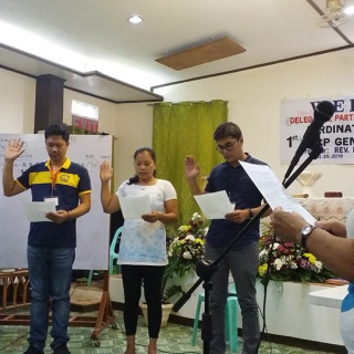 Four people stand holding up right hand to take oath, at UU Church of the Philippines