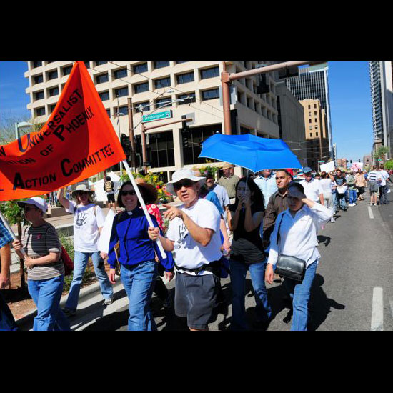 Members of the Unitarian Universalist Congregation of Phoenix Social Action Committee march in a demonstration, holding a banner that identifies them. Photo by George Pauk.