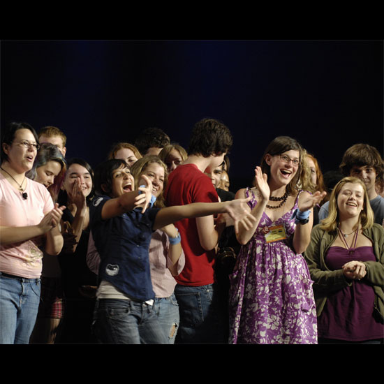 Youth, cheering, clapping, and holding their arms out to celebrate their friends. Photo by Nancy Pierce.