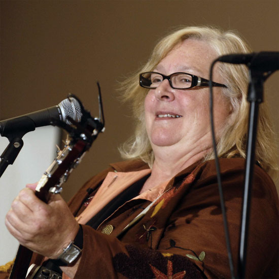 Meg Barnhouse, playing her guitar at a microphone. Photo by Nancy Pierce.