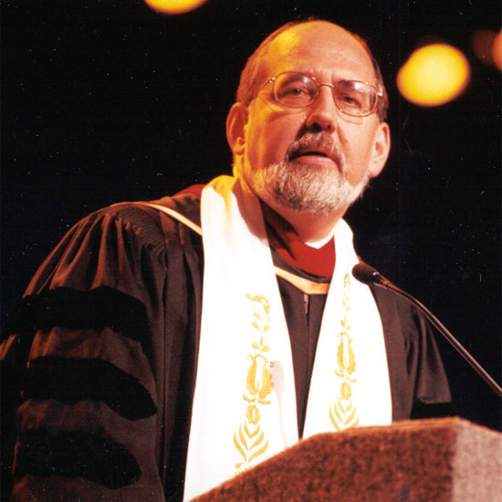 John Buehrens, speaking at a microphone in his ministerial robes. Photo by Nancy Pierce.