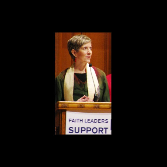Rev. Louise Green, performing a reading at a podium with a sign reading 'Faith Leaders Support LGBT Equality.' Photo by Orelia Busch/UUA.