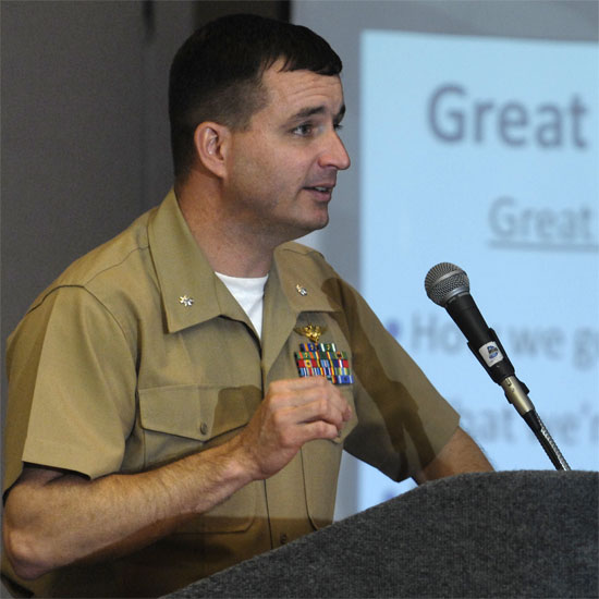 Seanan Holland, speaking at a microphone. Photo by Nancy Pierce.