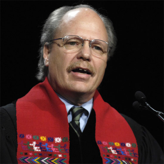 Fred Muir, in his ministerial robes, speaking into a microphone. Photo by Nancy Pierce.
