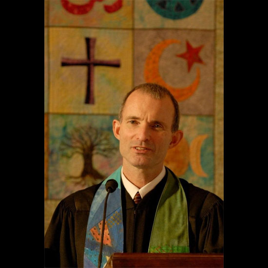 Fred Small, preaching in front of a tapestry with various religious symbols. Photo courtesy Richard Howard.
