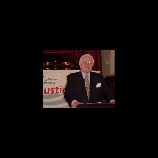 Edward M. Kennedy, speaking at a podium in front of a sign for 'Let Justice Roll.' Photo by UUA/Deborah Weiner.