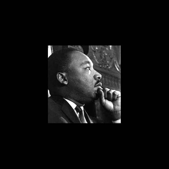 Dr. Martin Luther King, Jr. with his hand to his chin, listening. 
