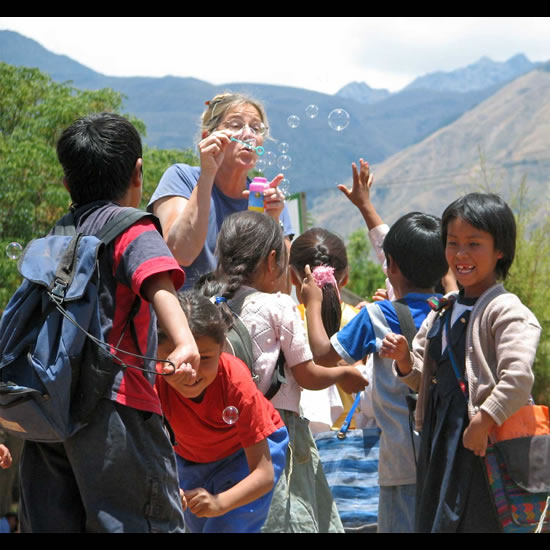 Amizade volunteer blows bubbles with children. 