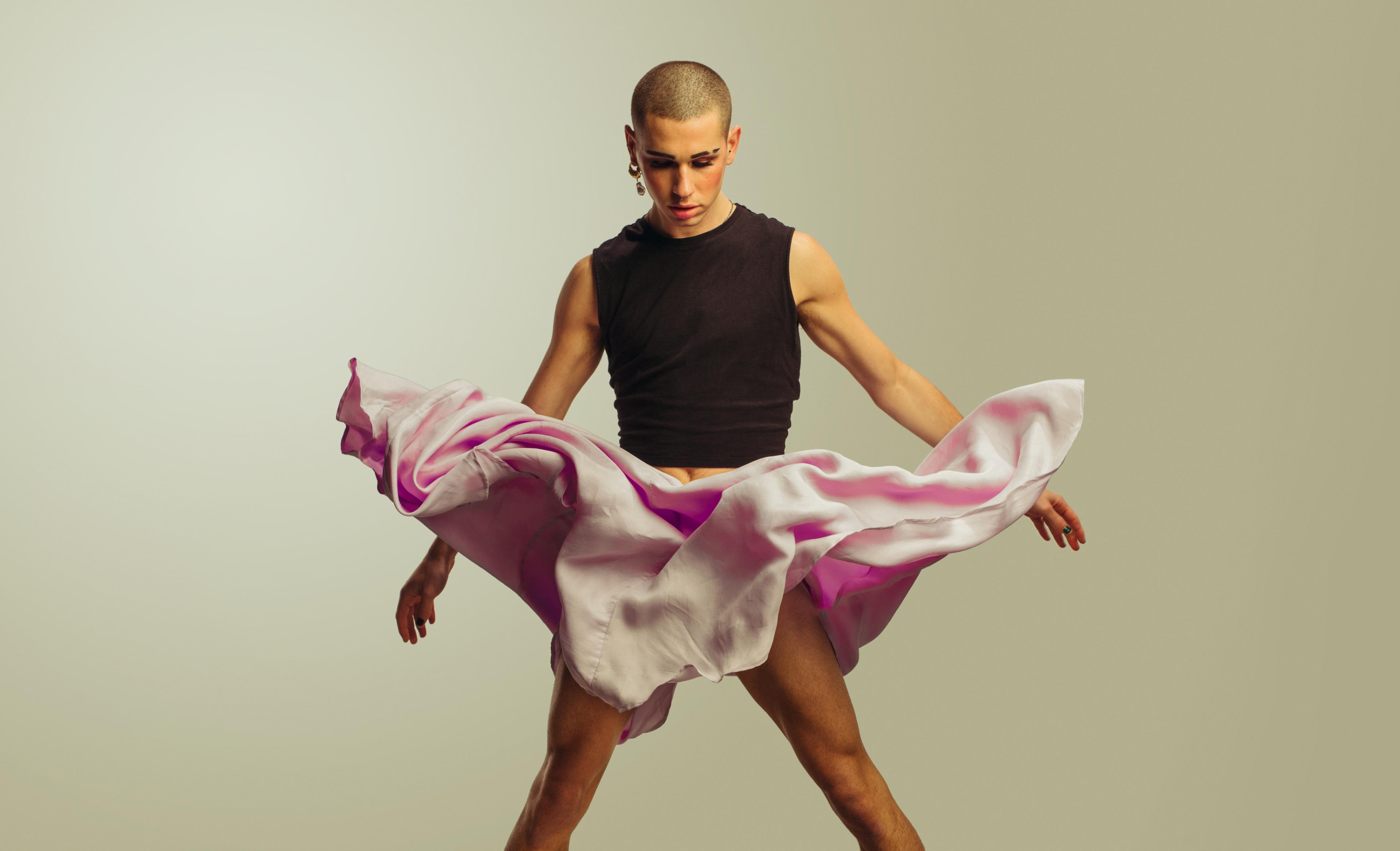 A gender fluid male, with very short hair, an earring, and makeup, with skirt fluttering in air