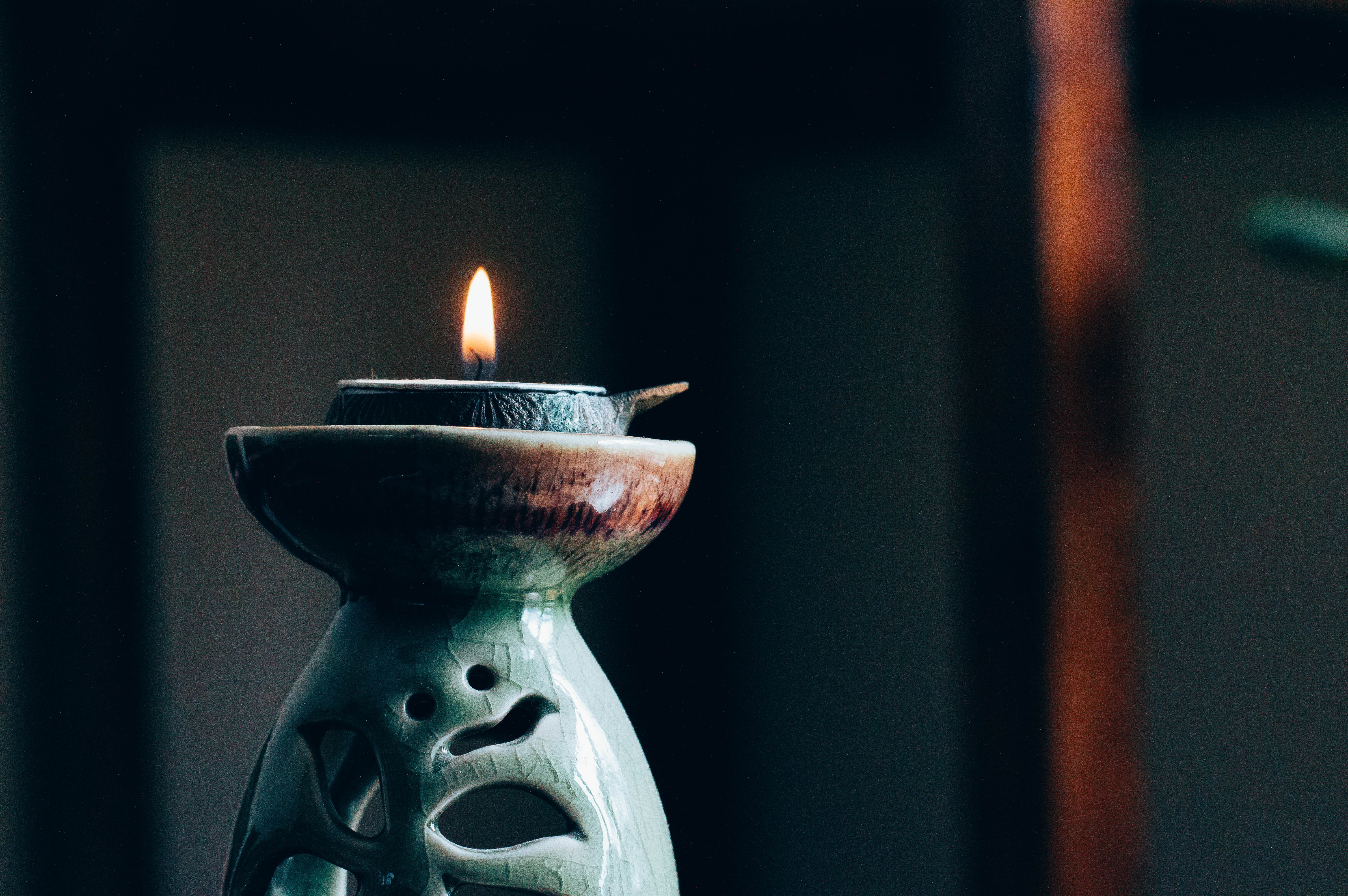 A small flame burns on a ceramic green candle holder