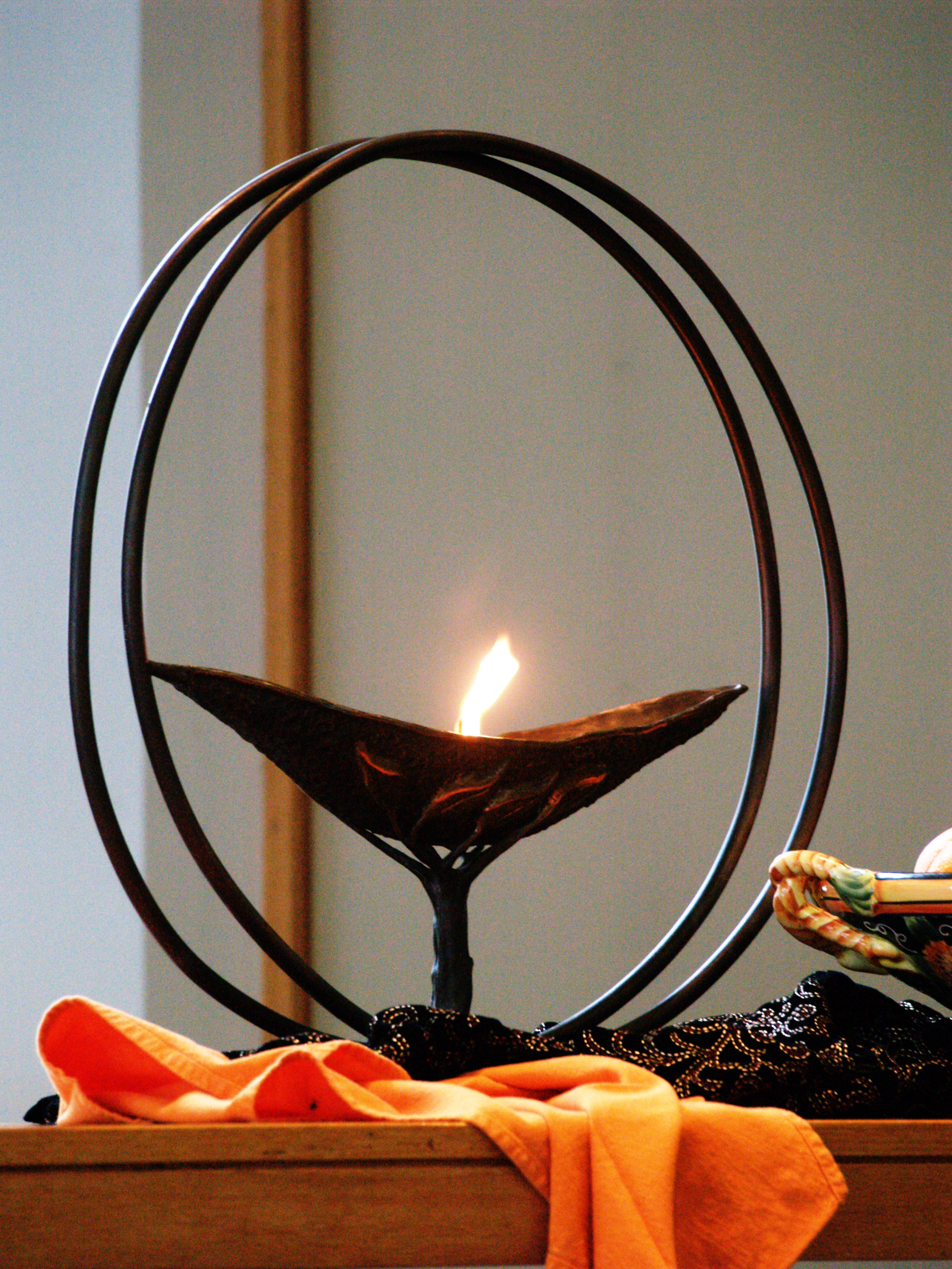 a flame inside of a graceful chalice, on an altar