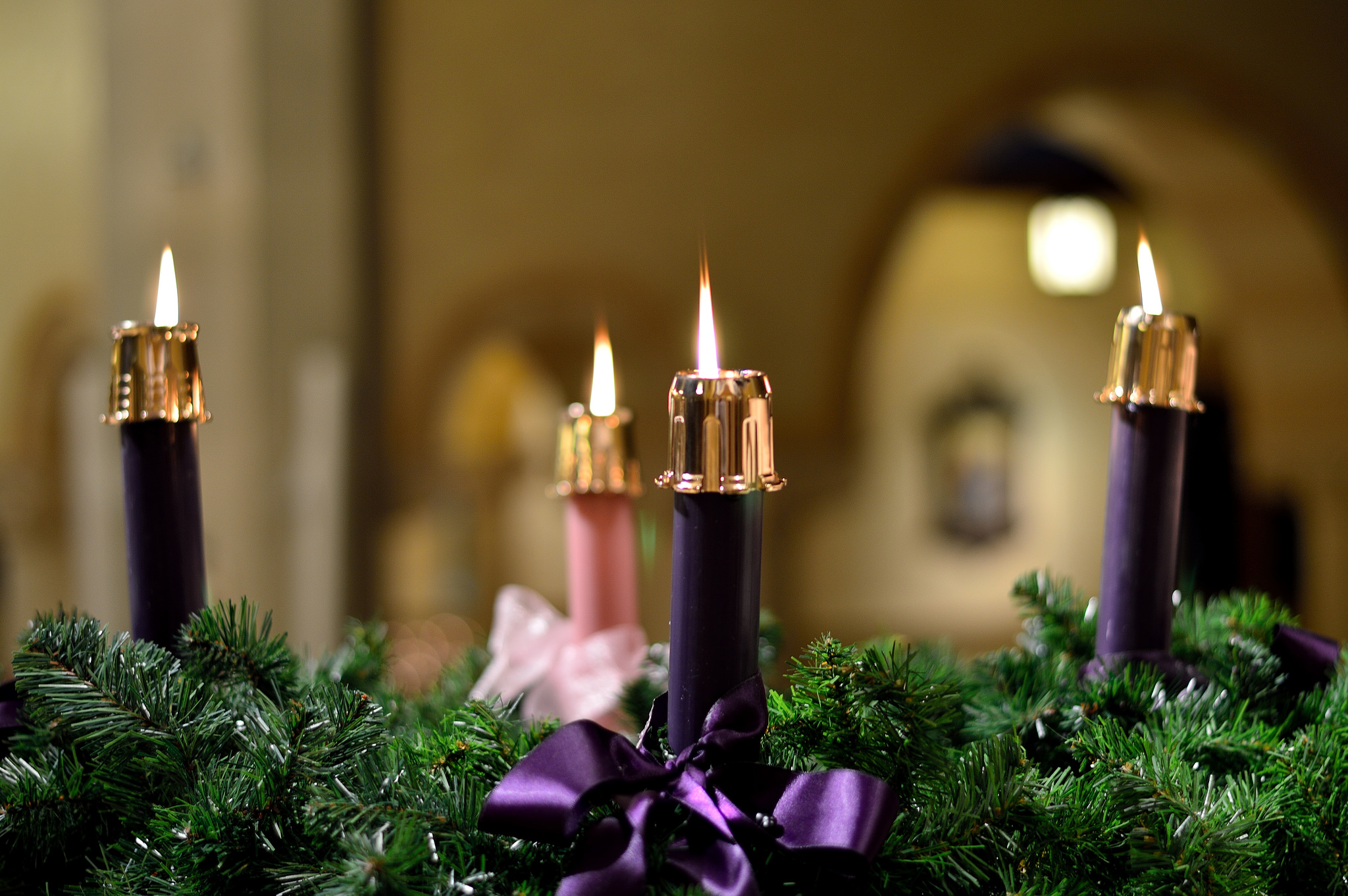 Three purple and one pink candles, all lit, on an Advent wreath