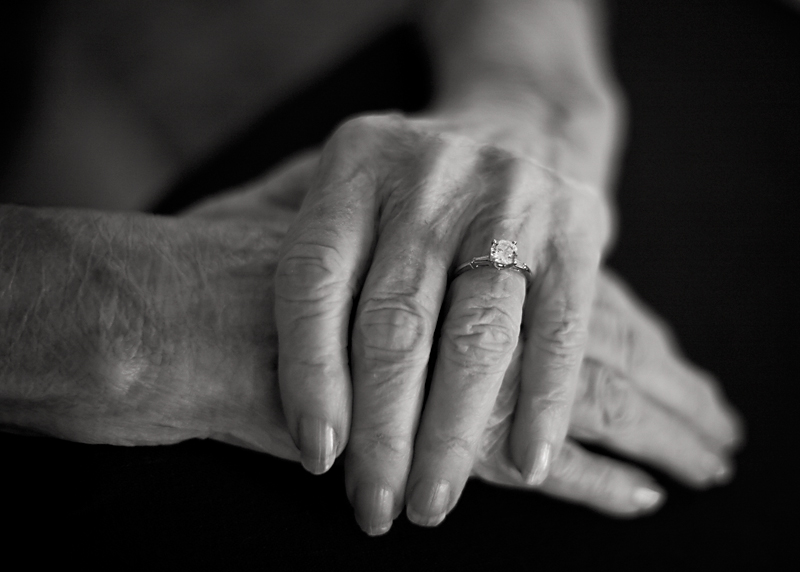 a black-and-white photo of a woman's wrinkled, graceful hands stacked on top of each other.