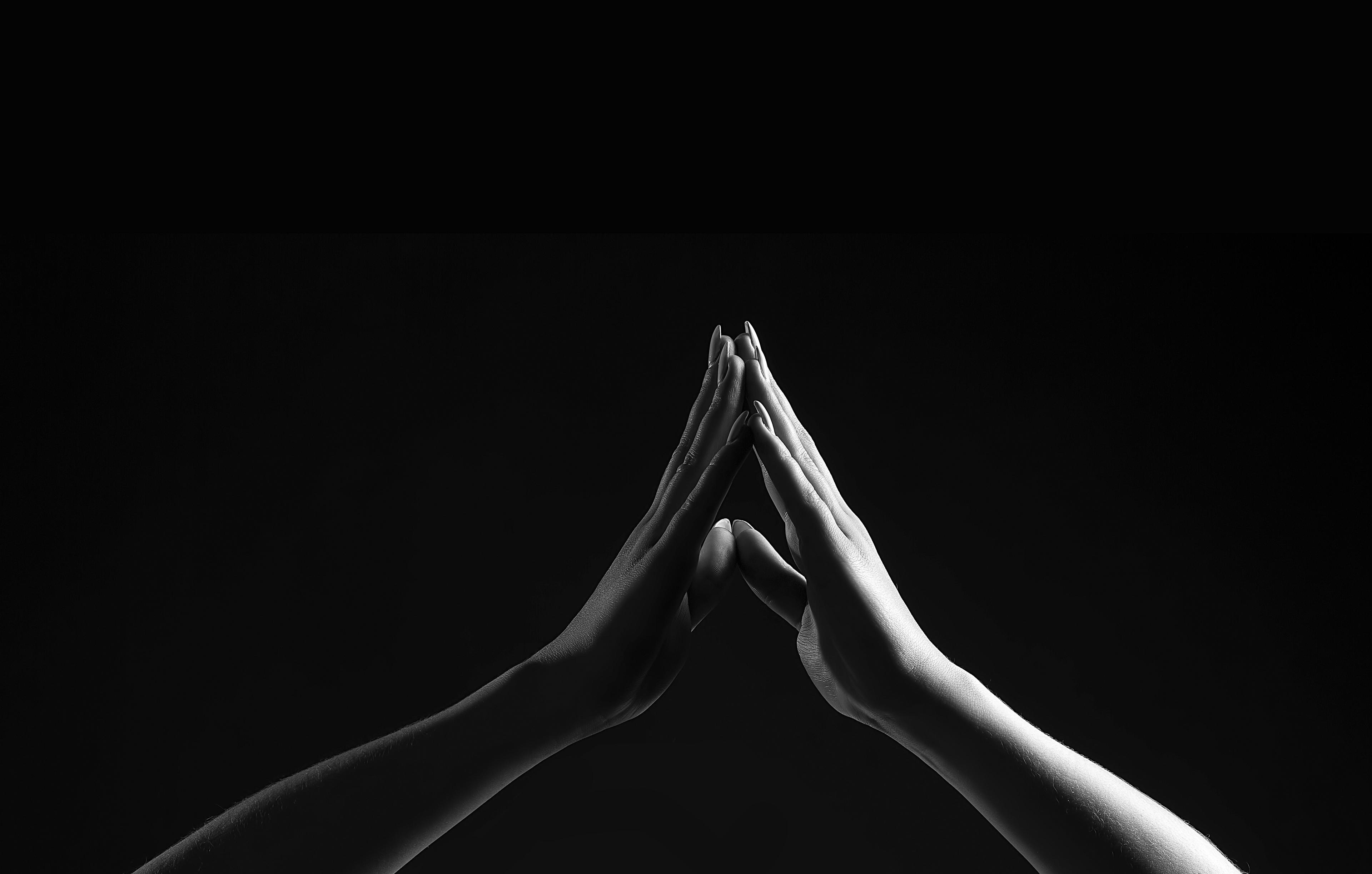 A person's hands and lower arms: the hands touch at the fingertips, palms separated, pointed upwards as if in prayer. 