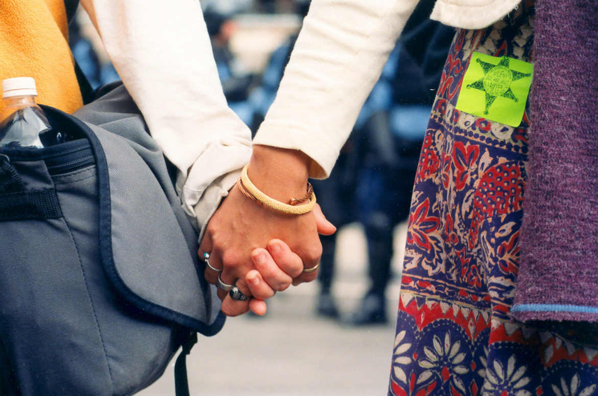 a close-up of two people's arms, and their linked hands.