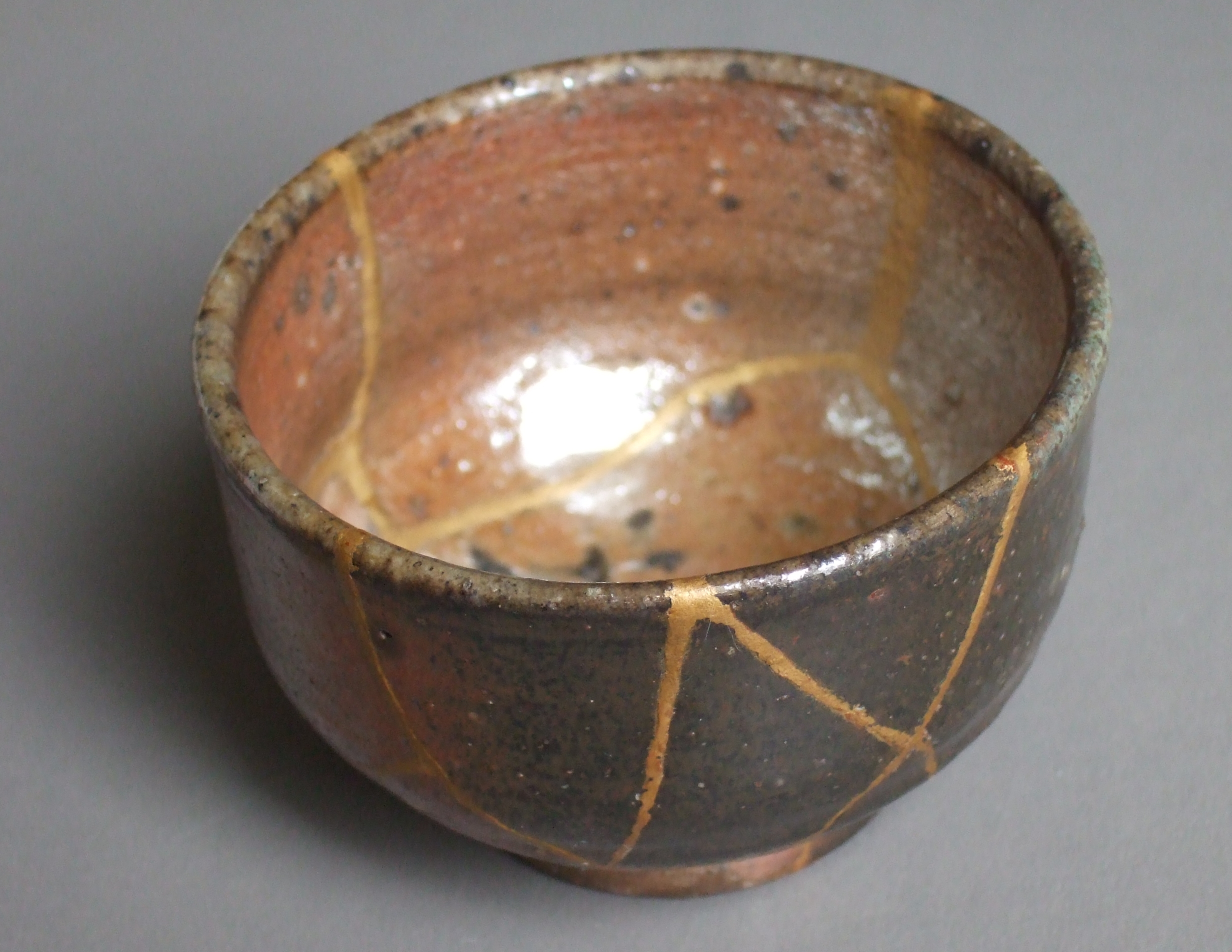 A pottery bowl with seams of gold showing where it's been made whole after breaking