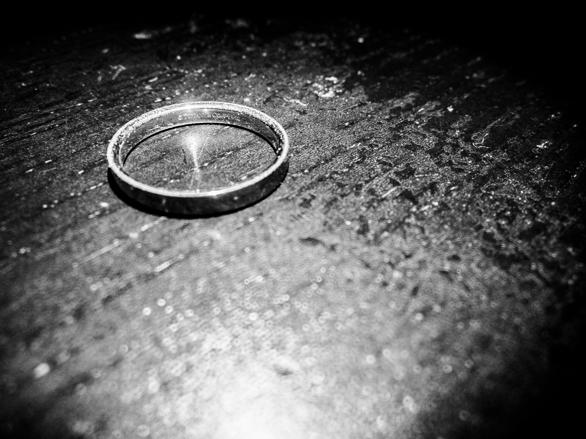 a black-and-white photo of a wedding band on a table