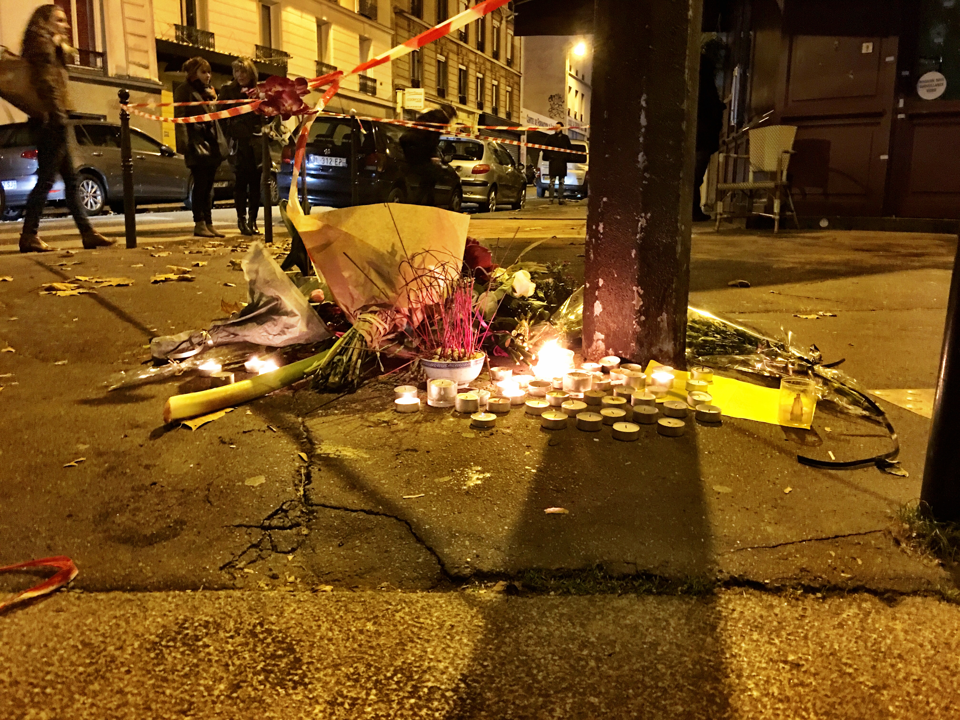 At the base of a street sign, a collection of small candles and flowers to honor victims of a terrorist bombing