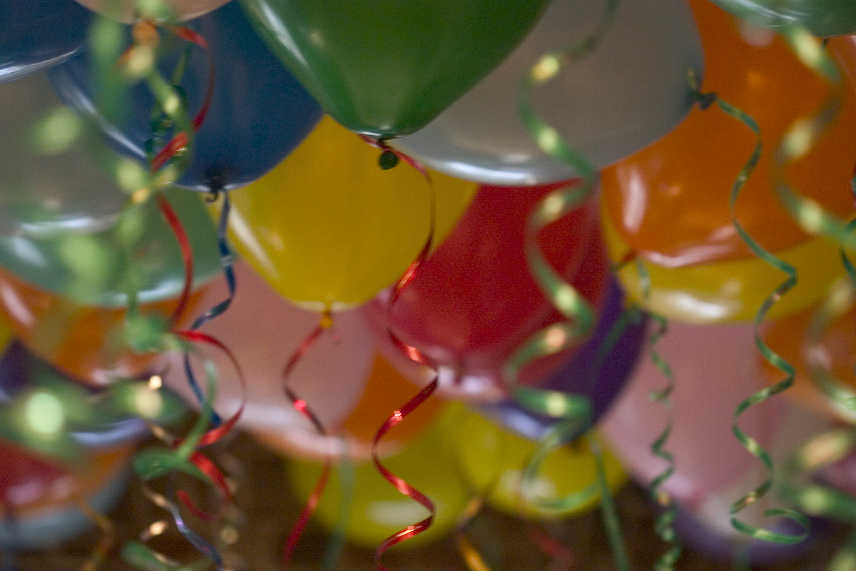 A cloud of helium balloons with shiny, curly ribbons