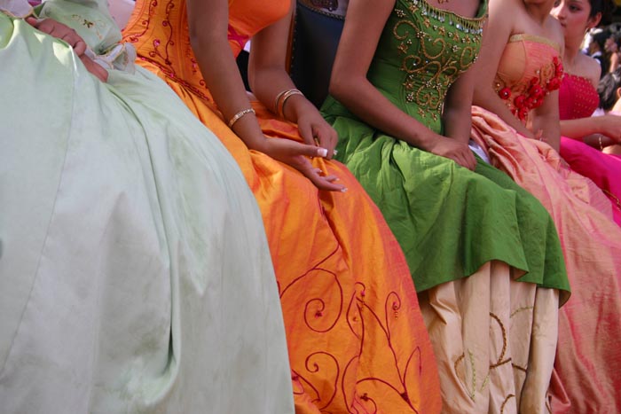 A row of young women, visible only from their shoulders to their ankles, in long colorful gowns.