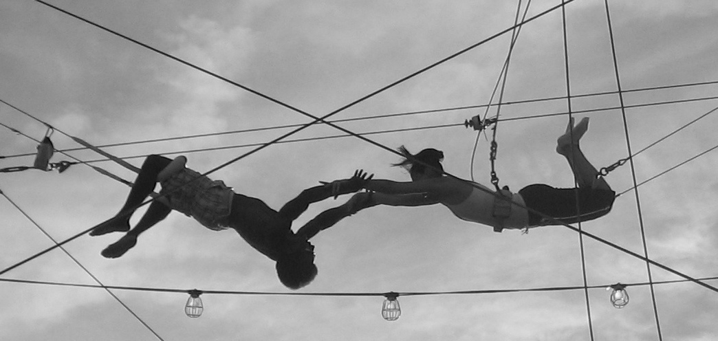 Two trapeze artists meet, mid-swing, for 