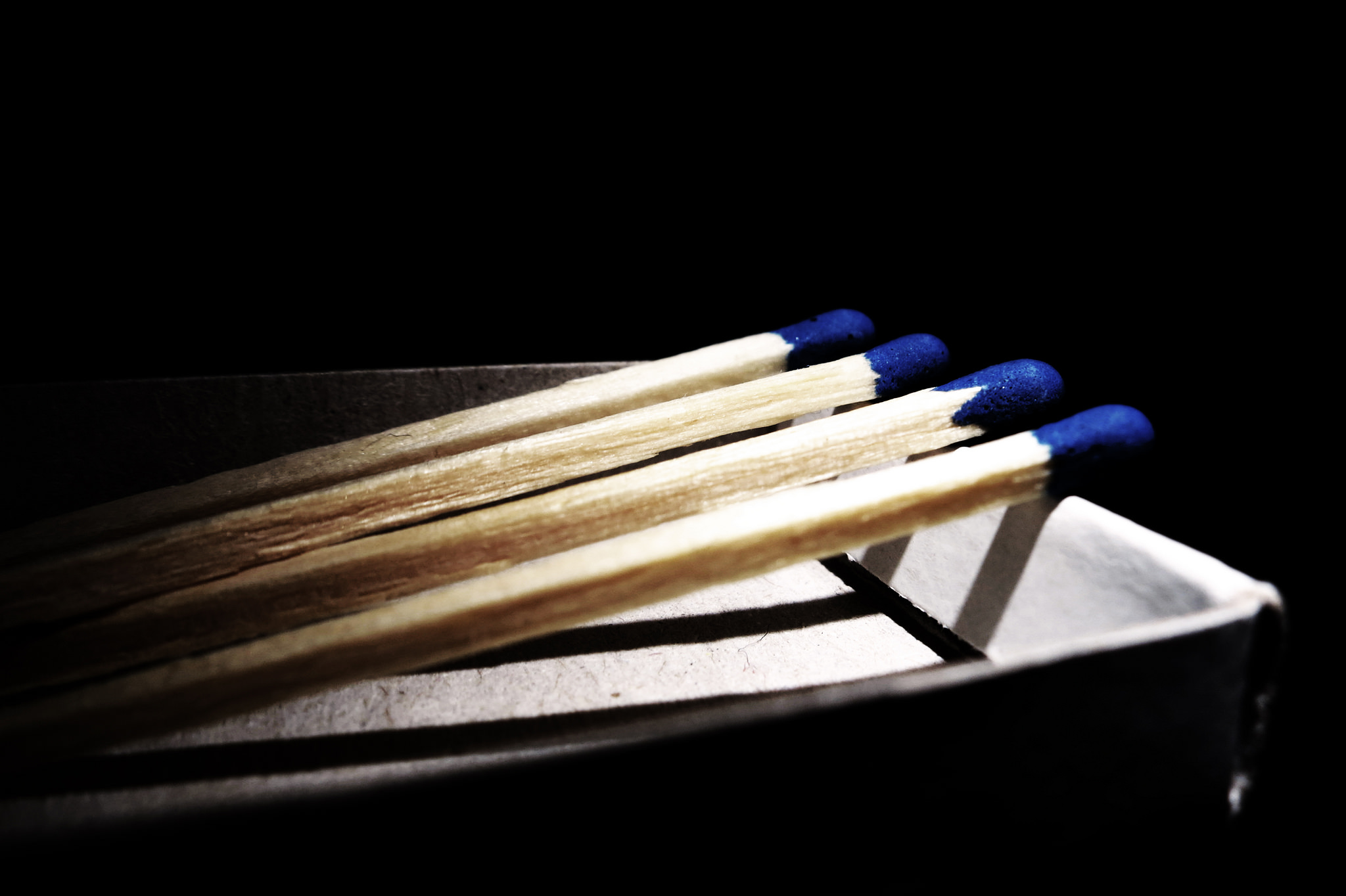 Four blue-tipped matches, resting on the edge of a box.