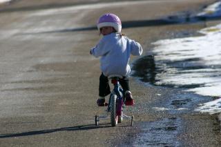 child riding a bike with training wheels looking backwards