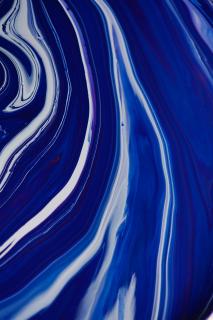close up - flowing bright blue paint, white reflections on the ridges