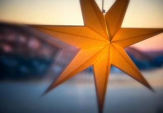 A glowing paper star lantern appears to hang in a window, with a winter scene outside.