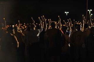 Crowd gathered holding lights up at nighttime.