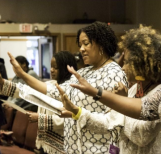 Black women raising their hands in worship