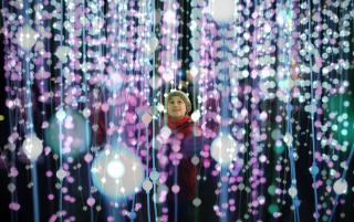 a child smiles up in wonder amid multiple vertical strings of light