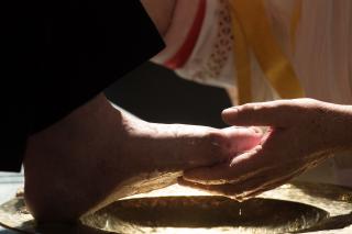 A hand cupping a person's foot in the process of footwashing during a Maundy Thursday Mass.