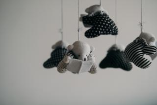 small fabric teddy bears, connected in a mobile, are suspended over an imagined baby's bassinet
