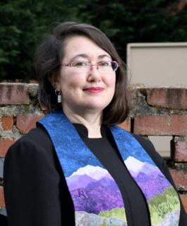 Trustee Rev. Elizabeth Mount, a person with brown hair, wearing a multicolor stoll and glasses.
