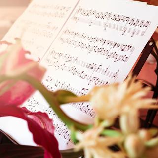 sheet music on a music stand surrounded by flowers