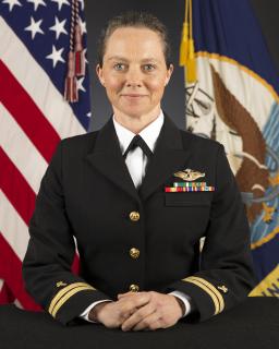 In her formal military portrait, Susan Maginn poses solemnly in her dress uniform in front of the US flag.