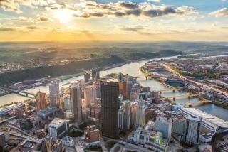 ariel view of the Pittsburgh skyline with sun and clouds on the horizon