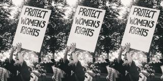 Three identical black-and-white images side-by-side of person at protest holding sign reading "Protect Women's Rights"