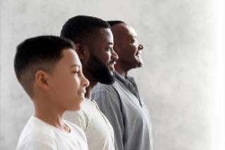 Seen from the chest up, a side view of three generations: a Black son, father, and grandfather standing side by side.