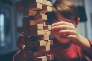A child carefully tries to remove a wooden block from a Jenga tower.