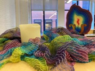 Colorful scarf draped around thick white candle with an artistic chalice flame in the background