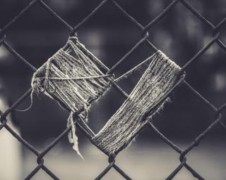 On a chain-link fence, frayed rope or twine has been used to weave a heart shape.