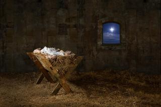 A straw-filled manger in a stable, with the Christmas star in the window