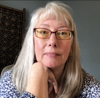 Photo of white woman with long gray hair and glasses.