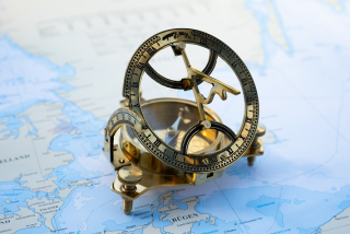 Antique brass magnetic sundial compass on top of a map.