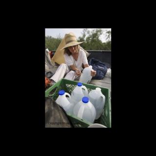 A woman labels gallon water jugs.